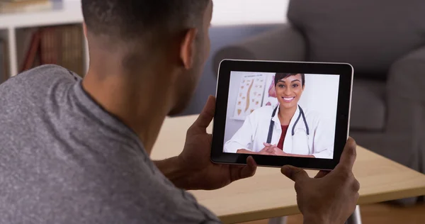 Black man listening to doctor on tablet