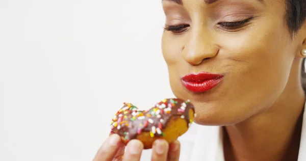 African American woman indulging in delicious chocolate donut with sprinkles