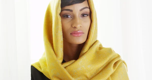 Beautiful African woman wearing gold head scarf in bright room