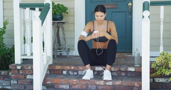 Hispanic woman starting playlist before going out for a run