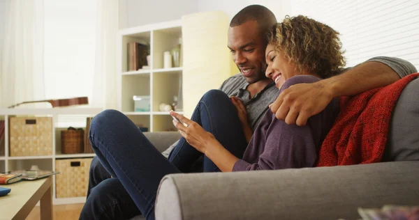 African American couple using devices on couch