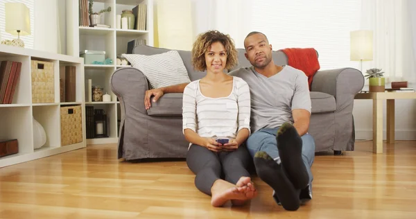 Cute black couple sitting on floor in living room