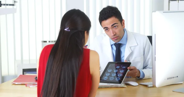 Hispanic doctor reviewing brain xrays with patient at desk