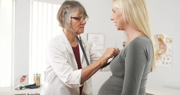 Doctor listening to pregnant woman\'s heart