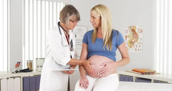 Happy doctor touching pregnant woman's belly