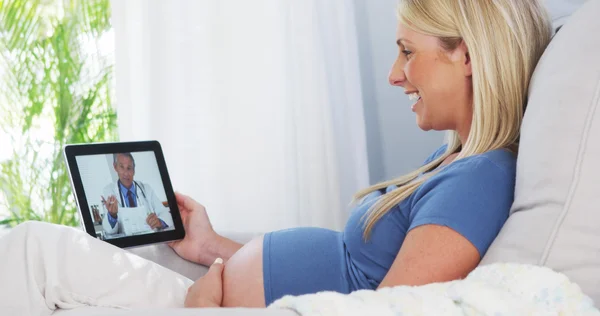 Pregnant woman video chatting with doctor on tablet