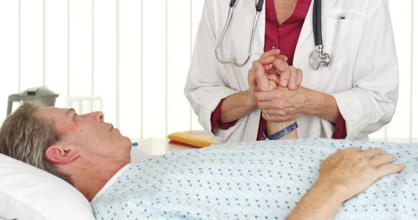 Doctor holding patient's hand and comforting him