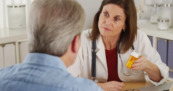 Elderly patient talking doctor about prescription in office