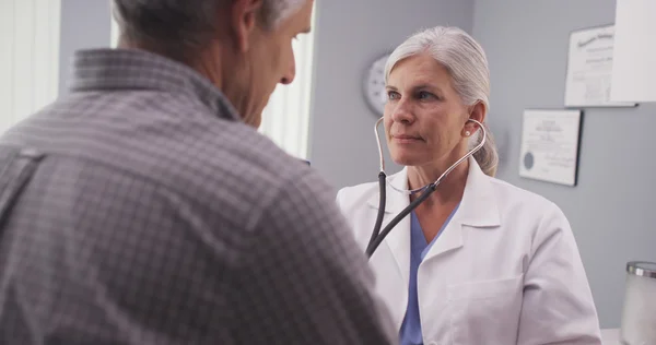 Doctor listening to patient\'s heart rate with stethoscope