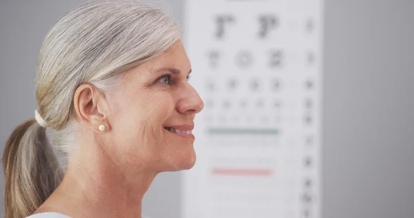 Mature woman receiving eyeglasses from optometrist