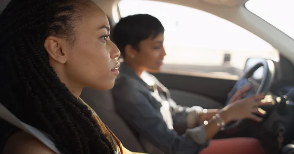Two black women friends sitting in car talking to each other