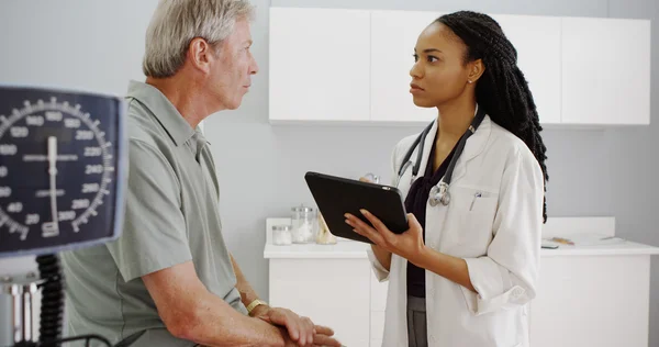 Black woman doctor checking senior's health records