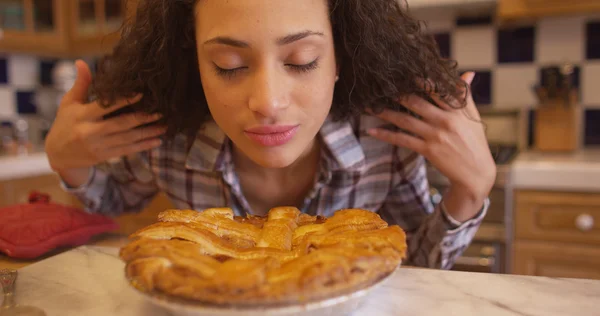 Charming young mixed ethnic woman smelling apple pie
