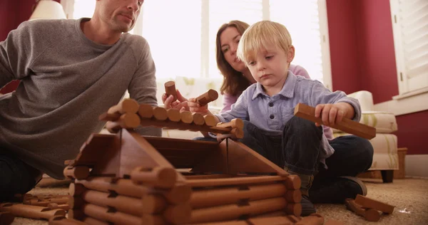 Adorable young children building a wooden house with family