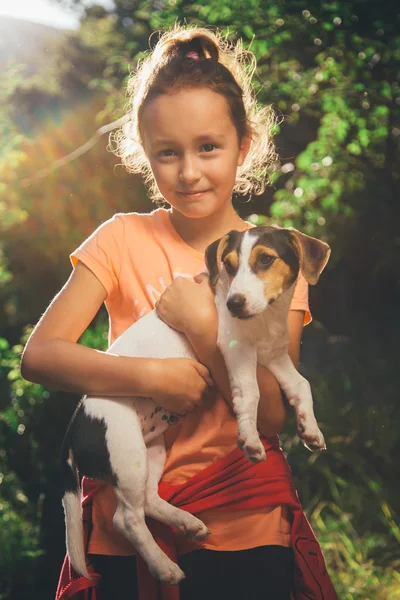 Girl holding a dog smiling and looking at camera