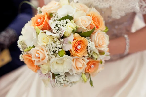 Pastel wedding bouquet with orange roses in hands