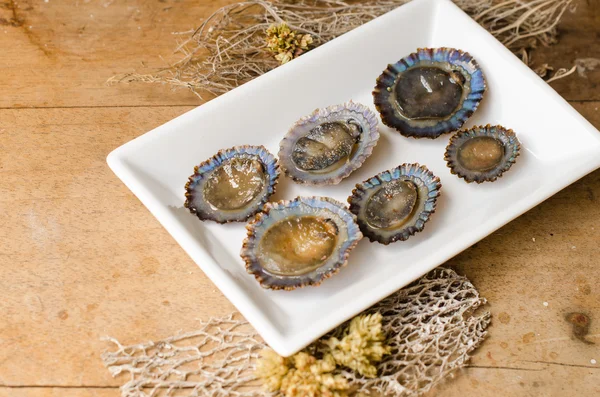 Raw limpets, rustic background.