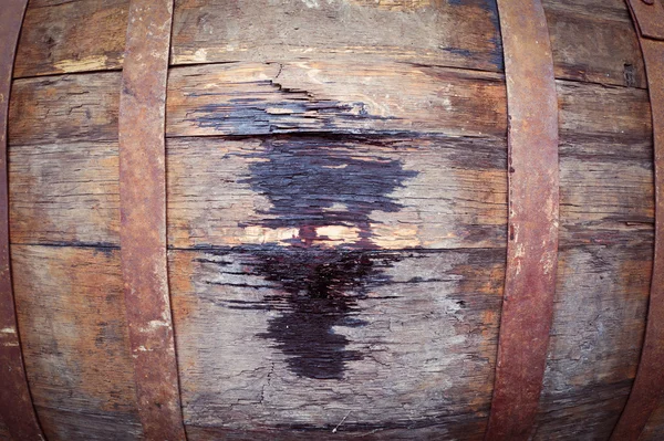 Close up of old oak wine barrel with wine drips, leak traces. Contents are leaking down the side of barrel.
