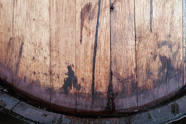 Close up of old oak wine barrel with wine drips, leak traces. Contents are leaking down the side of barrel.