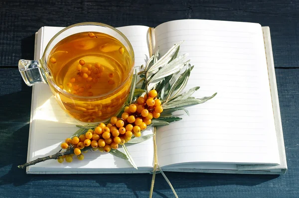 Sea buckthorn tea and open pure notebook.