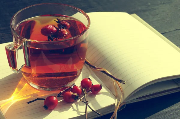 Rosehip tea and open pure notebook.