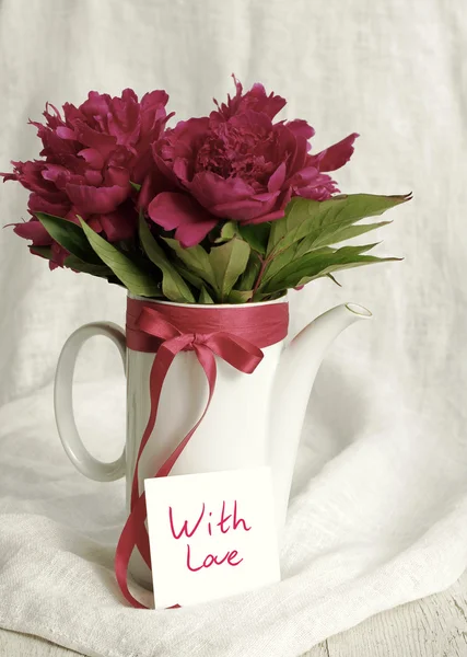 With love. Bouquet of pink peonies and the white card  with the inscription 