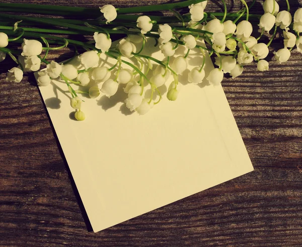 Bouquet of lilies of the valley and the empty white card for an inscription