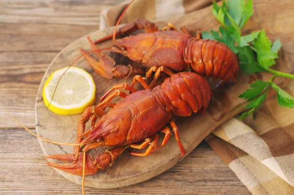 Boiled crawfishes on a wooden board on a wooden background