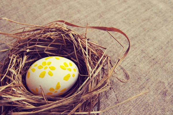 Easter egg with bright drawing in a nest from a dry grass