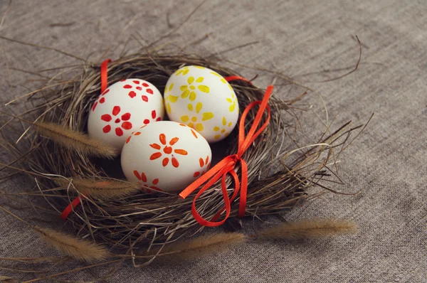 Two Easter eggs with bright drawing in a nest from a dry grass