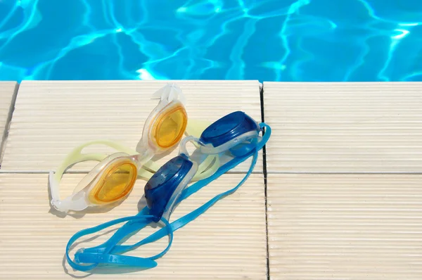 Points for swimming under water near the pool. Summer holiday. Two couples sport glasses for swimming