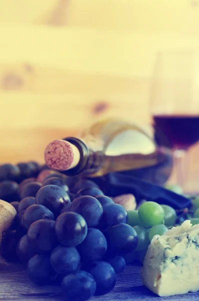 Bottle of red wine, grapes and wine traffic jams on a wooden surface