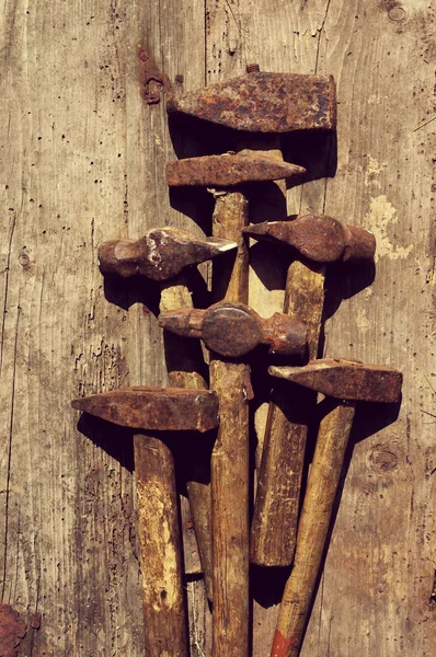 Old rusty hammers on a textural wooden surface. Old tools