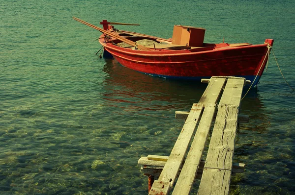 Red Mediterranean fishing boat in the sea in a summer sunny day. Lonely red boat