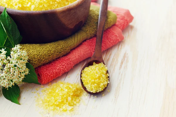 Aromatic salt for Spa therapies in a wooden bowl, with a towel and sea stones.