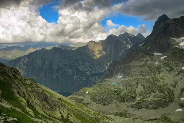 Two lakes hidden high in mountain in between rocky peaks under tragic cloudy sky