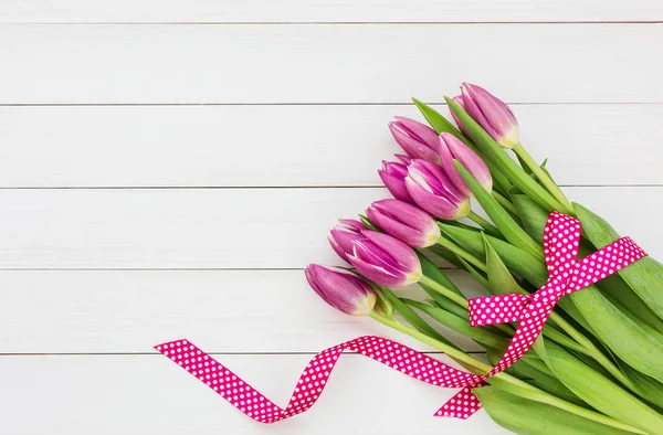 Bouquet of bright pink tulips on white wooden background. Top view
