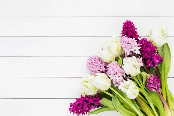 Bouquet of pink hyacinth flowers and white tulips on white wooden background