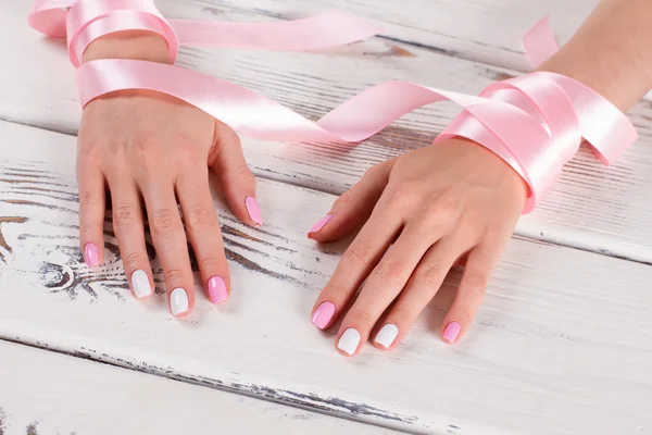 Female hands tenderly entwined with pink ribbon.