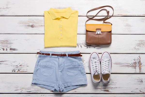 Bright yellow polo shirt and denim shorts.