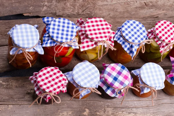 Jars with fruits and vegetables on vintage background.