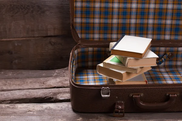 Books in an old leather checkered suitcase.