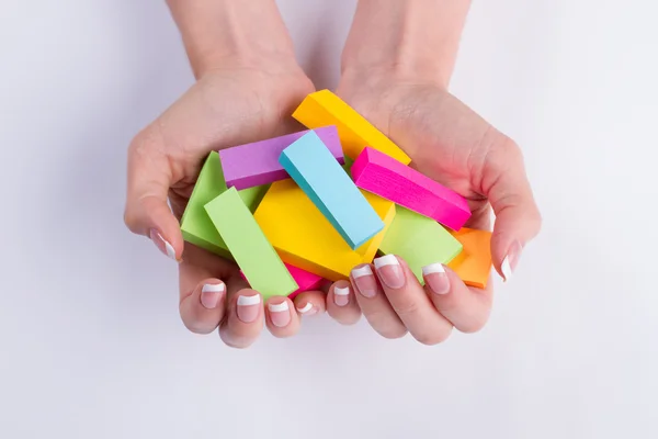Multi-colored paper stickers in the hands.