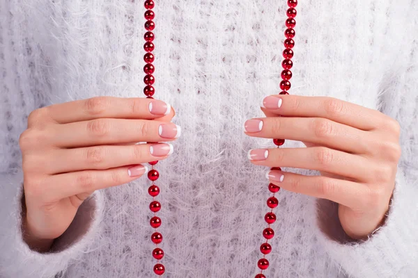 Female fingers holding a red necklace.