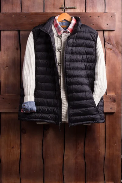 Shirt, sweater and vest on a wooden fence.