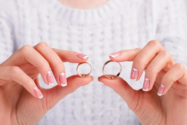 Beautiful female fingers holding wedding rings.