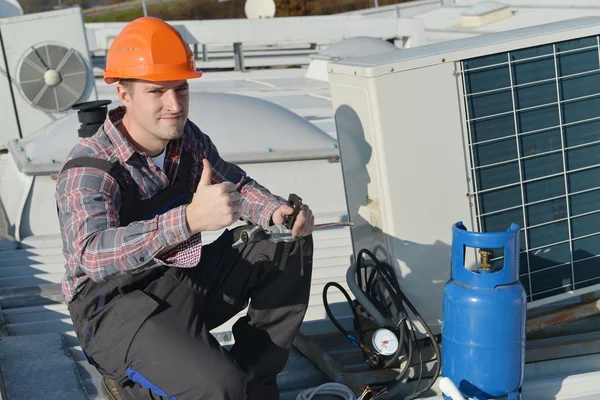 Young repairman on the roof fixing air conditioning system