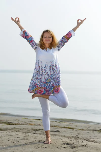 Young woman doing yoga on a rocky ocean shore