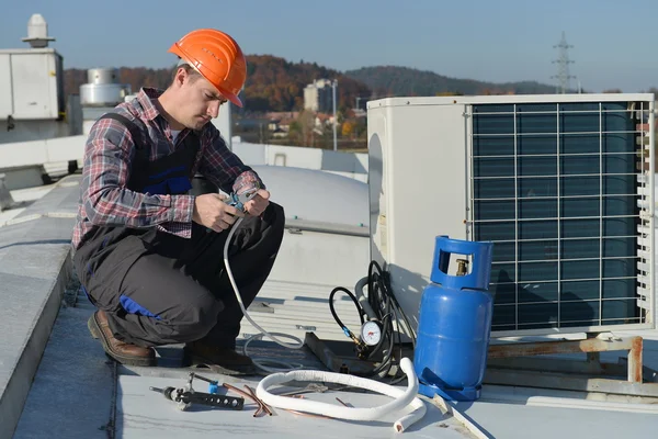 Young repairman on the roof fixing air conditioning system