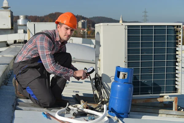 Young repairman fixing air conditioning system